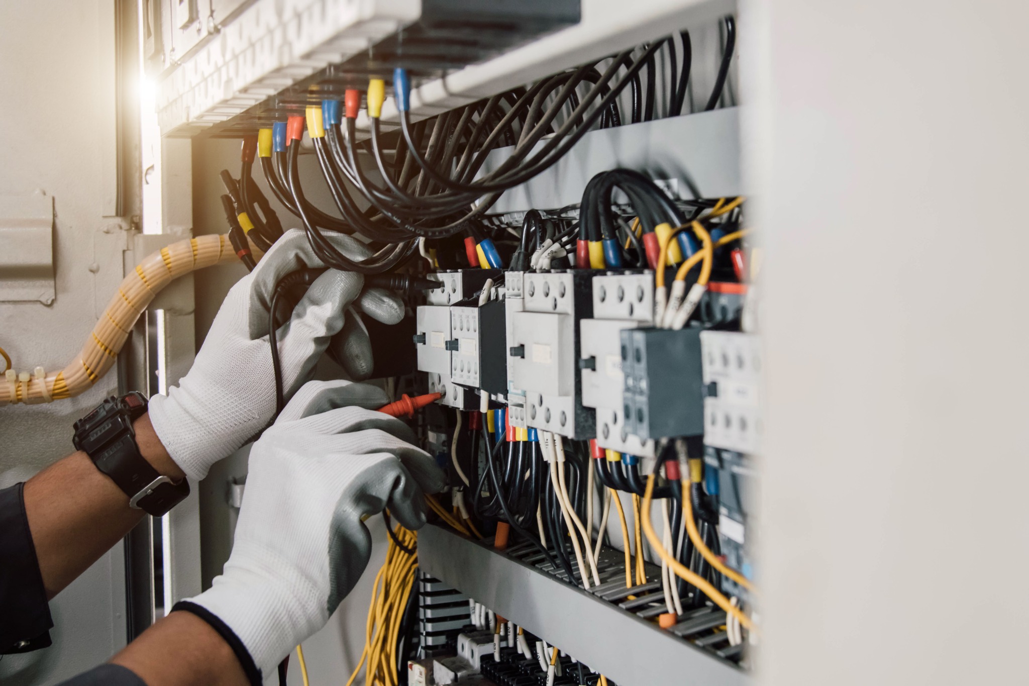 Technician working with wires and cables in an electrical control panel